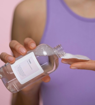 Woman pouring skincare product on a cotton pad.