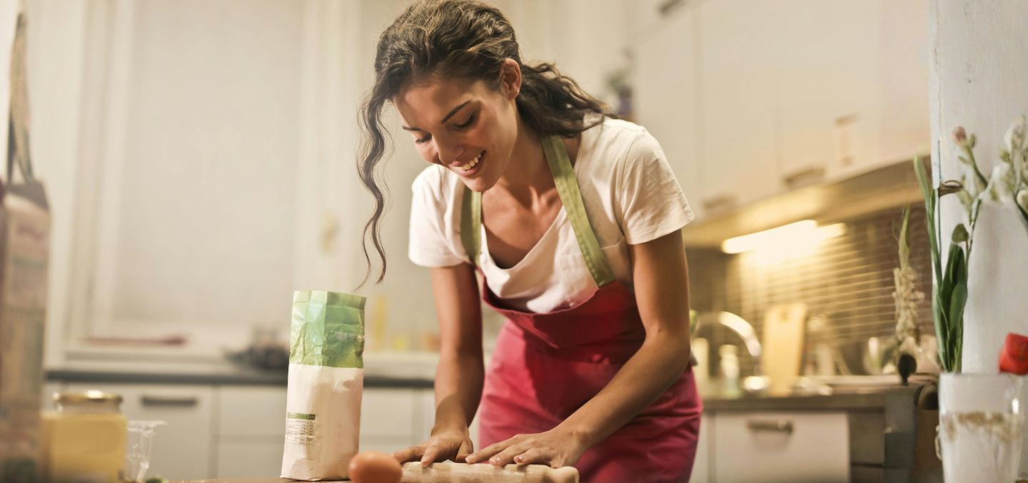 Woman in her kitchen using a rolling pin.