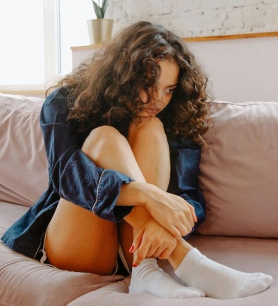 Woman crouched up over her couch in pain