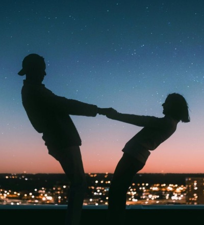 Couple dancing together and holding hands in front of a starry sky. Horoscope for couples as venus enters gemini.