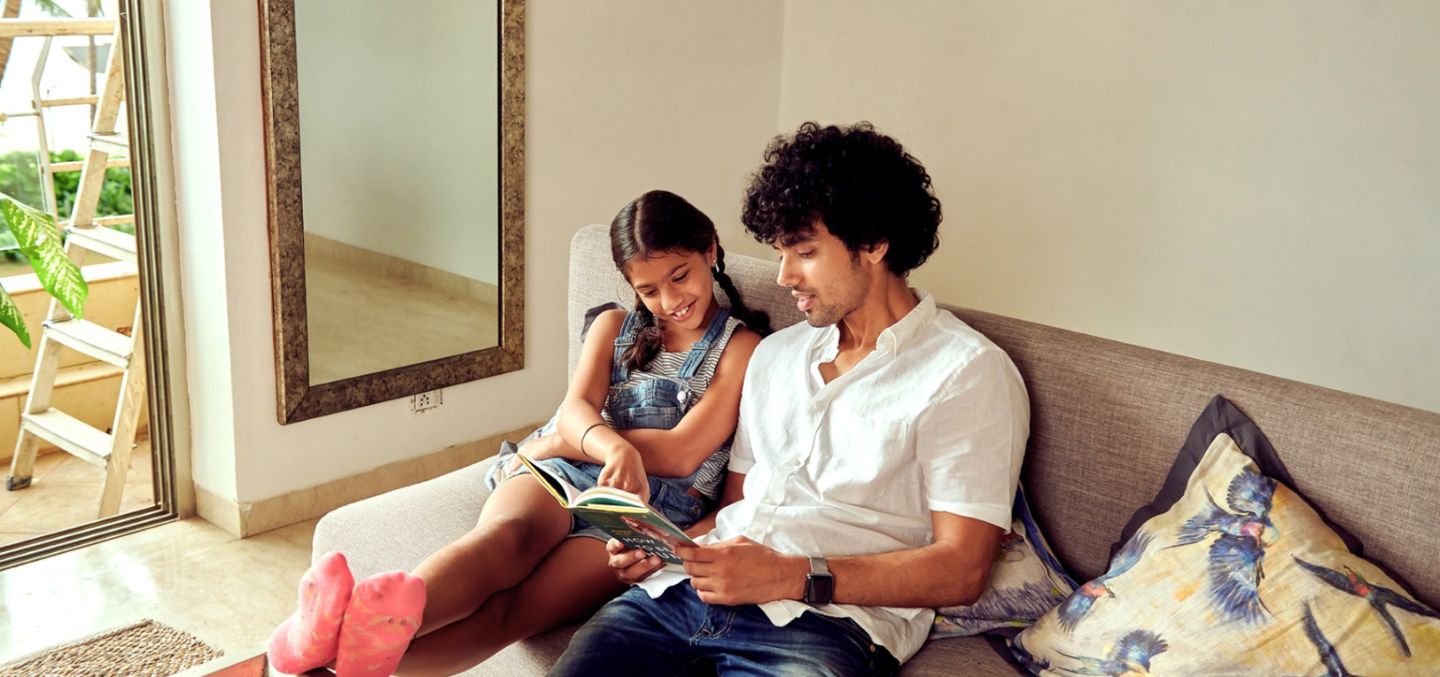 Father and daughter reading on a couch together.